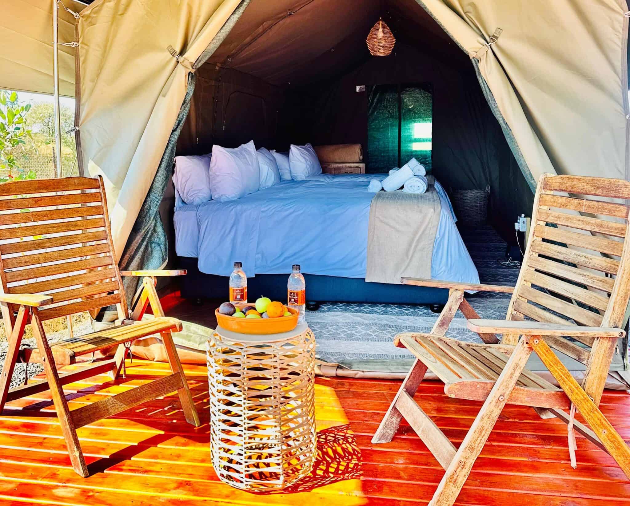 Elegant tent with a cozy bed and outdoor seating for safari guests.