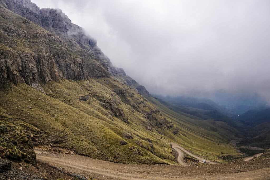 Scenic mountain landscape in Lesotho with winding dirt road and cloudy sky.