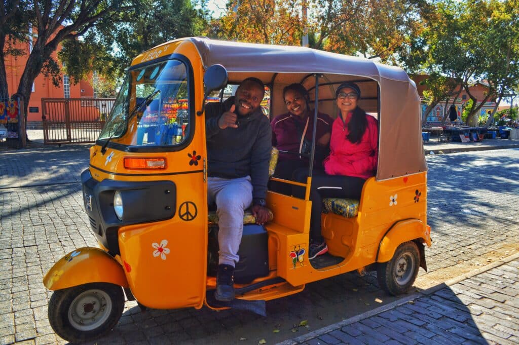 Colorful Soweto tuk tuk with happy tourists enjoying a tour.