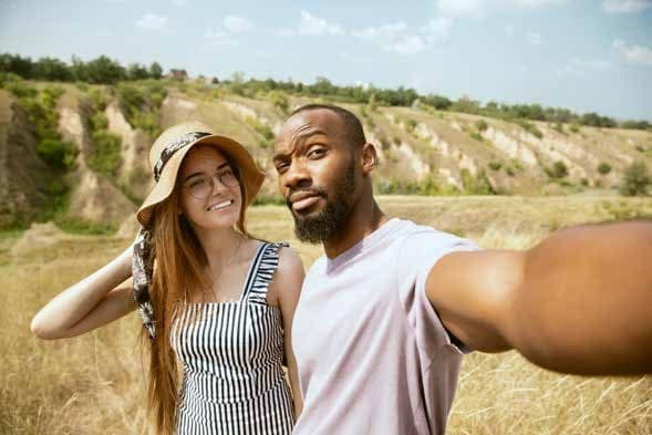 Couple taking a selfie during a nature tour with scenic landscape.