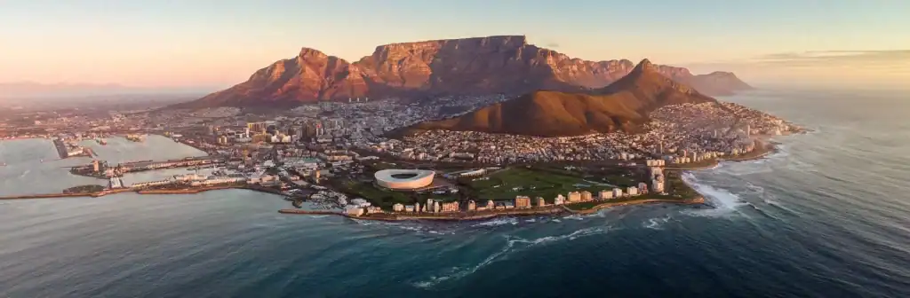 Aerial view of Cape Town with Table Mountain and coastline at sunset.