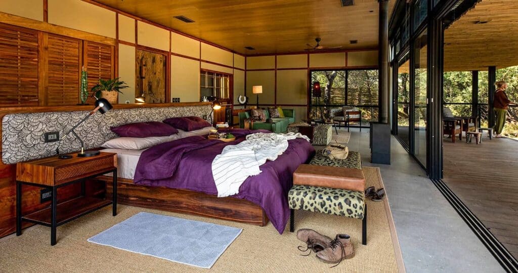 Elegant safari camp bedroom with large bed, cozy decor, and outdoor view.