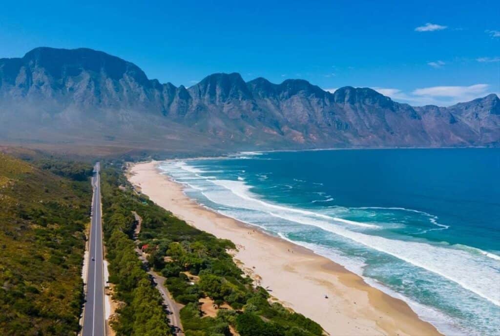 Beautiful coastal landscape with mountains, beach, and ocean waves.