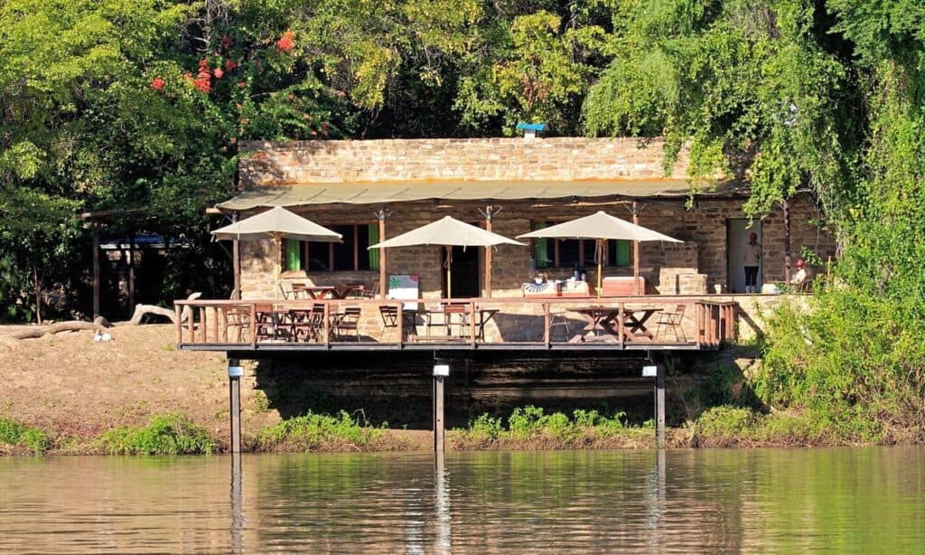 Riverside lodge with outdoor seating and umbrellas in Namibia.