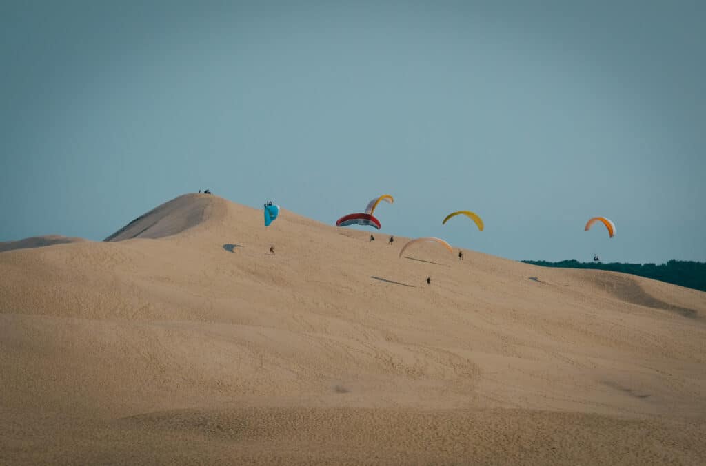 Paragliders flying over sand dunes in Namibia desert.